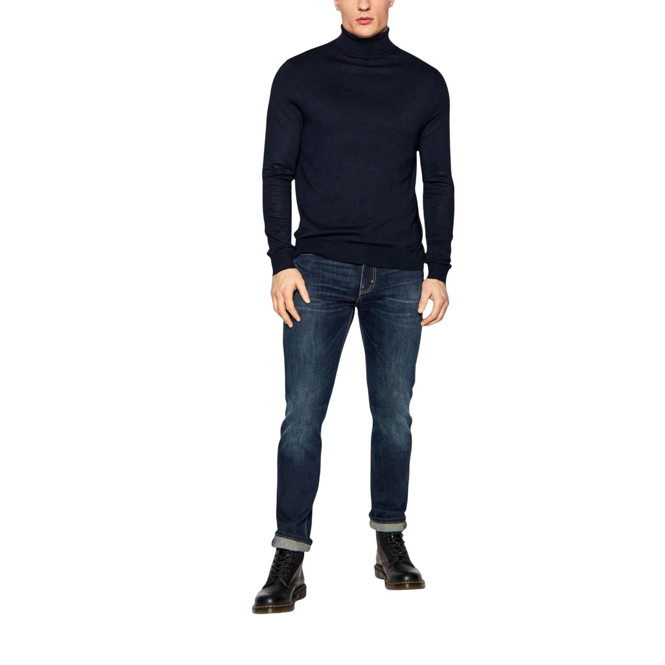 Person wearing a black turtleneck sweater and blue jeans on a white background