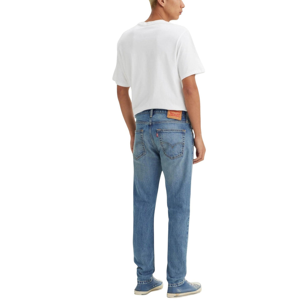 Person wearing blue jeans and a white t-shirt on a white background